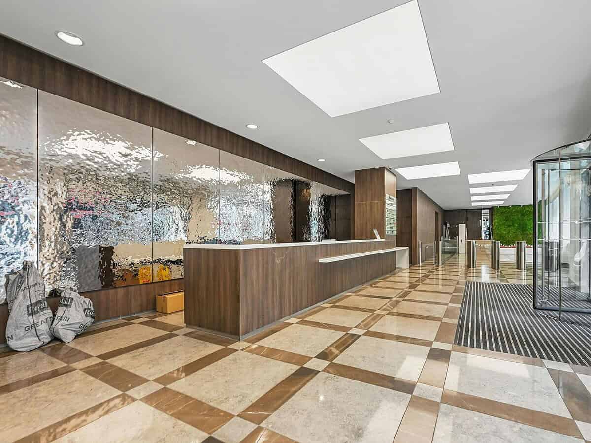 Modern hotel lobby with wooden accents, marble flooring, and sleek reception desk at BELCOR London.