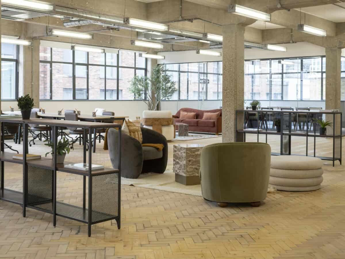 Modern industrial co-working space with stylish furniture and large windows for natural light.