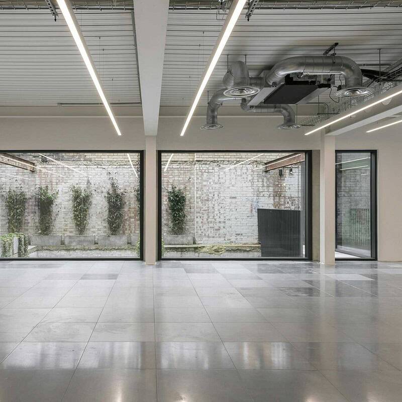 Spacious modern industrial office interior featuring large glass windows, polished concrete floors, and contemporary lighting, ideal for creative work environments and business offices.