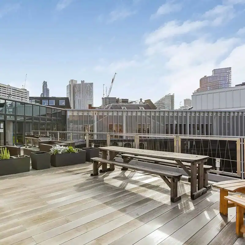 Modern rooftop terrace in Shoreditch with outdoor seating, planters, and city skyline views, perfect for work breaks or social gatherings.