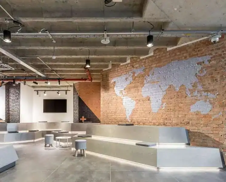 Contemporary office interior in Islington with exposed brick walls, world map mural, and minimalist furniture, showcasing a stylish workspace for businesses.