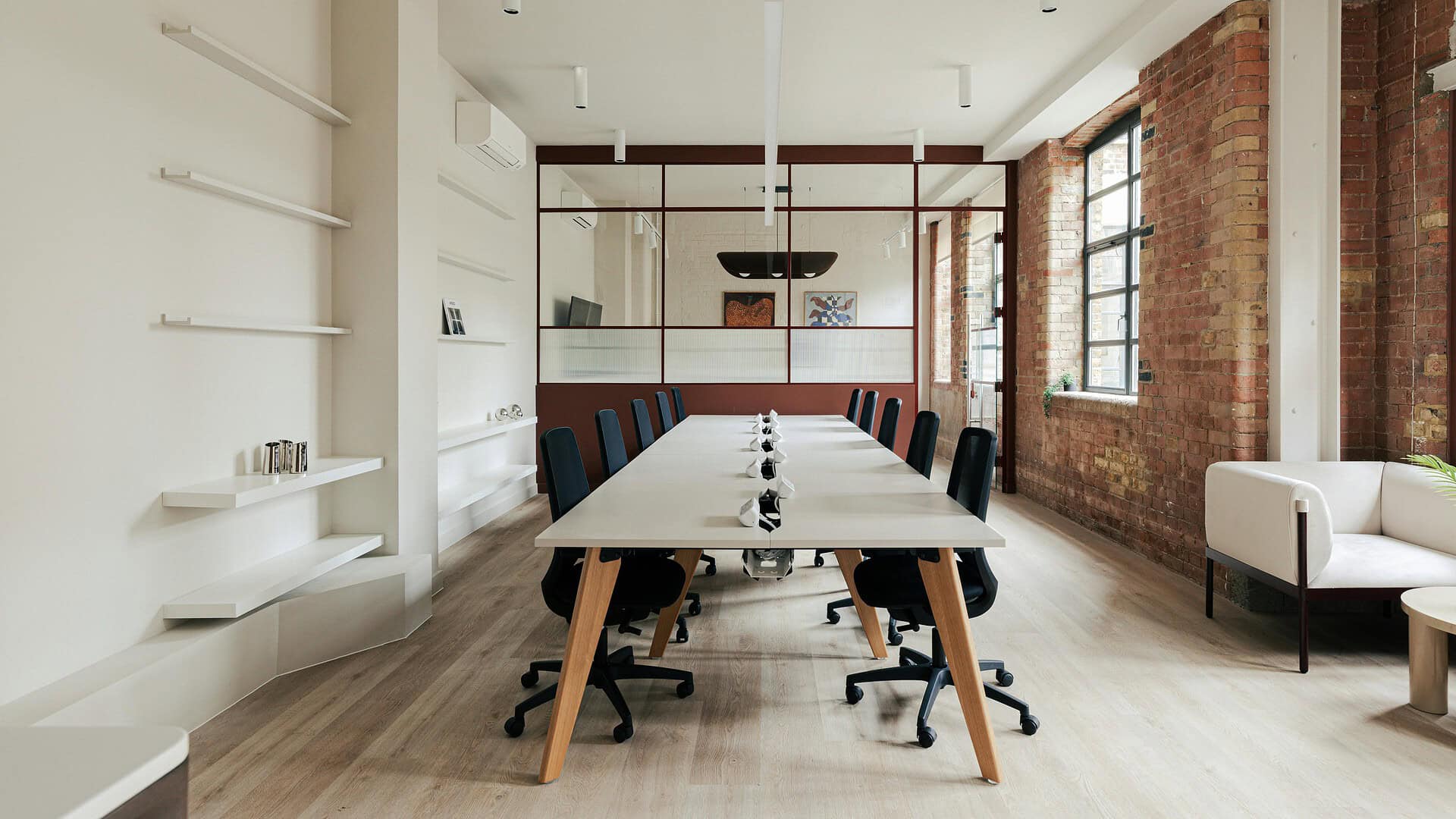 Bright and spacious office meeting room with a large table, black chairs, exposed brick walls, and natural light from large windows, ideal for team discussions at Jacks Place E1 6NH.