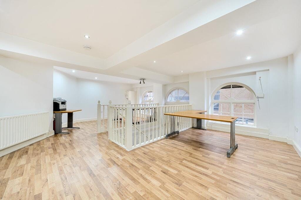 Bright, spacious living area with wooden flooring, large windows, and modern interior design in Fairchild Place, EC2A 3EN. Perfect for comfortable living and entertaining.