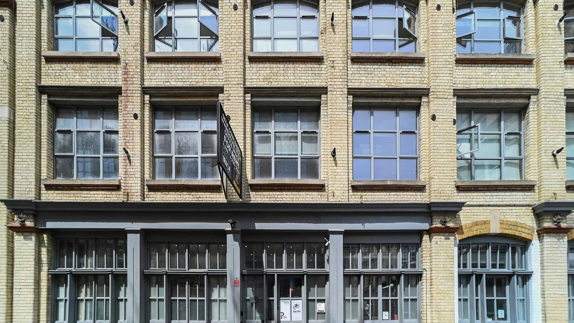 Exterior view of the historic brick building at Wood Lofts, 30-40 Underwood Street, showcasing large industrial-style windows and a modern ground-floor entrance.