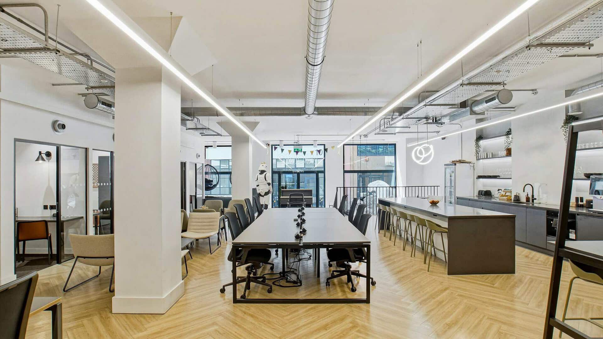 Spacious and modern office interior at 14 Bonhill Street EC2A 4BX, featuring a large conference table, contemporary chairs, and a sleek kitchen area, ideal for collaborative work.