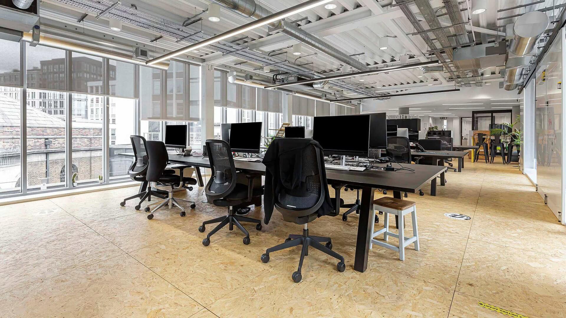 Spacious modern office with multiple workstations, ergonomic chairs, large monitors, and large windows with city views at BELCOR, Third Floor, 39 Tabernacle Street.