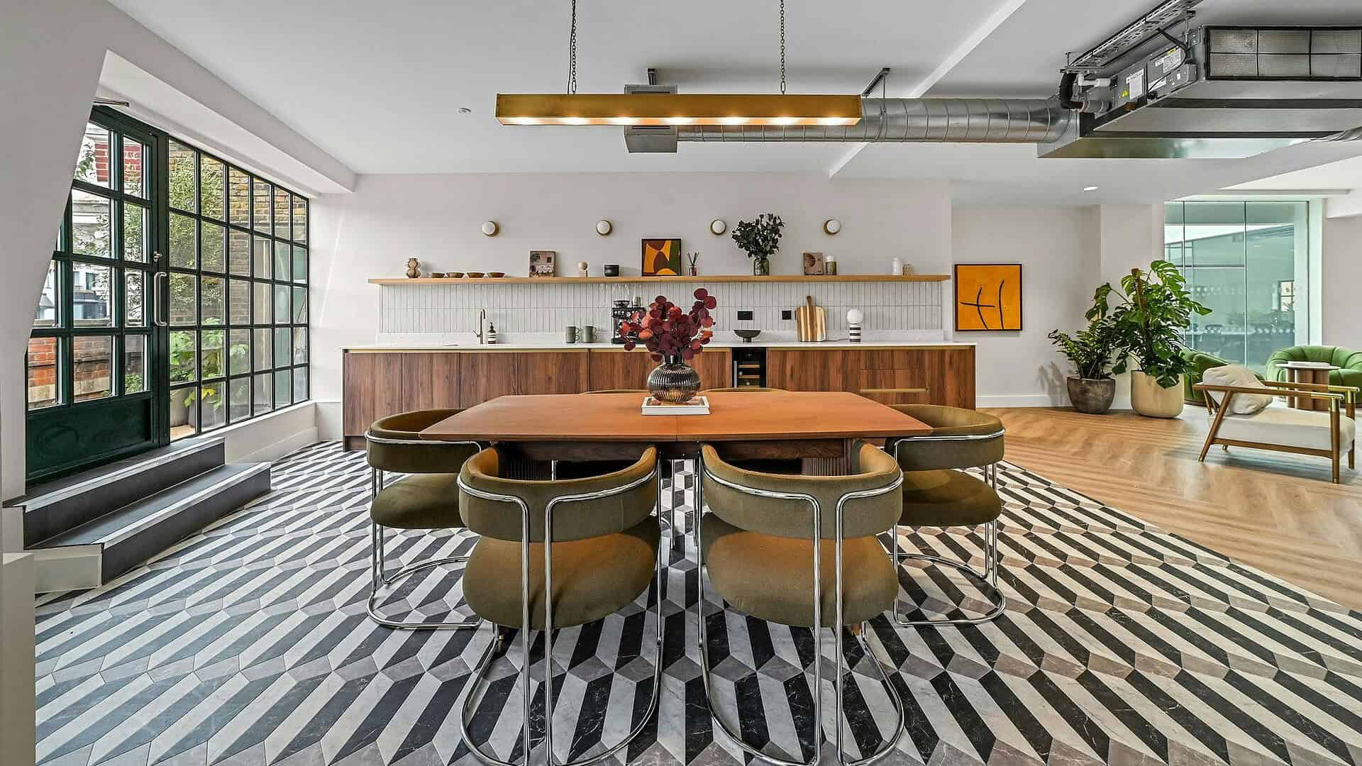 Contemporary office interior with a large wooden table, stylish chairs, geometric patterned rug, and modern decor in Shoreditch, London.