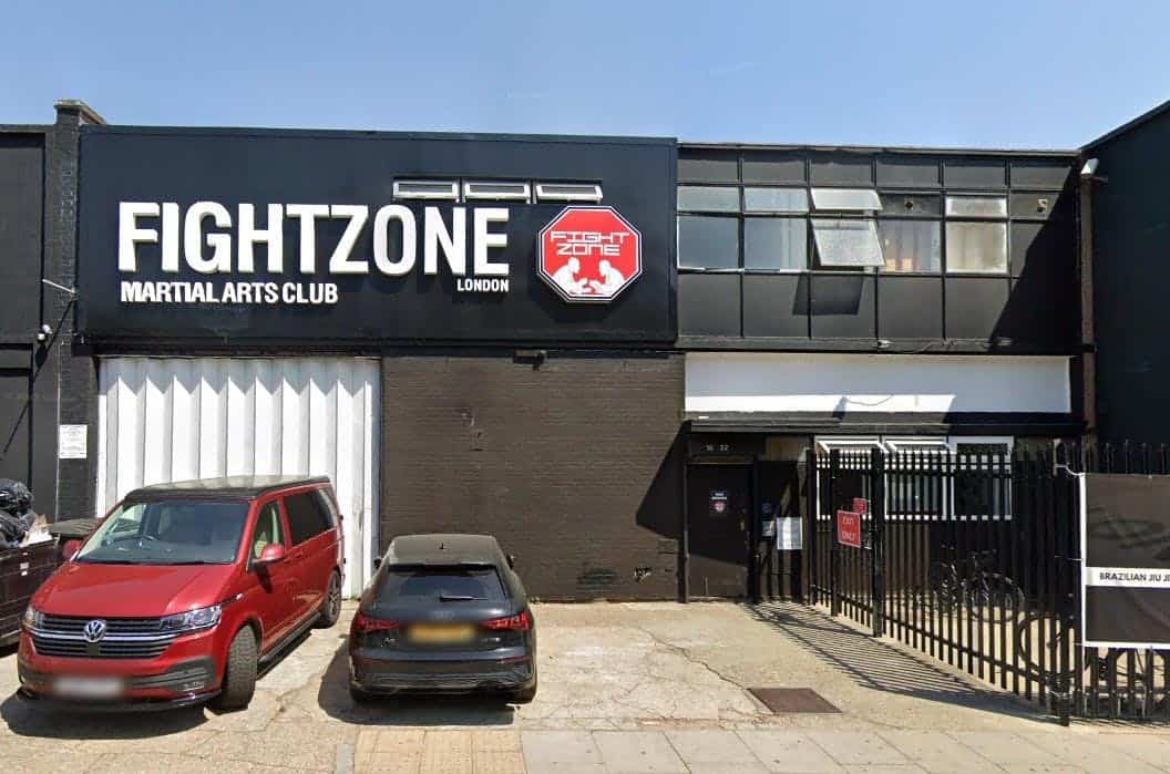 Exterior view of Fightzone Martial Arts Club in London, showing the black building with signage and parked cars in front.