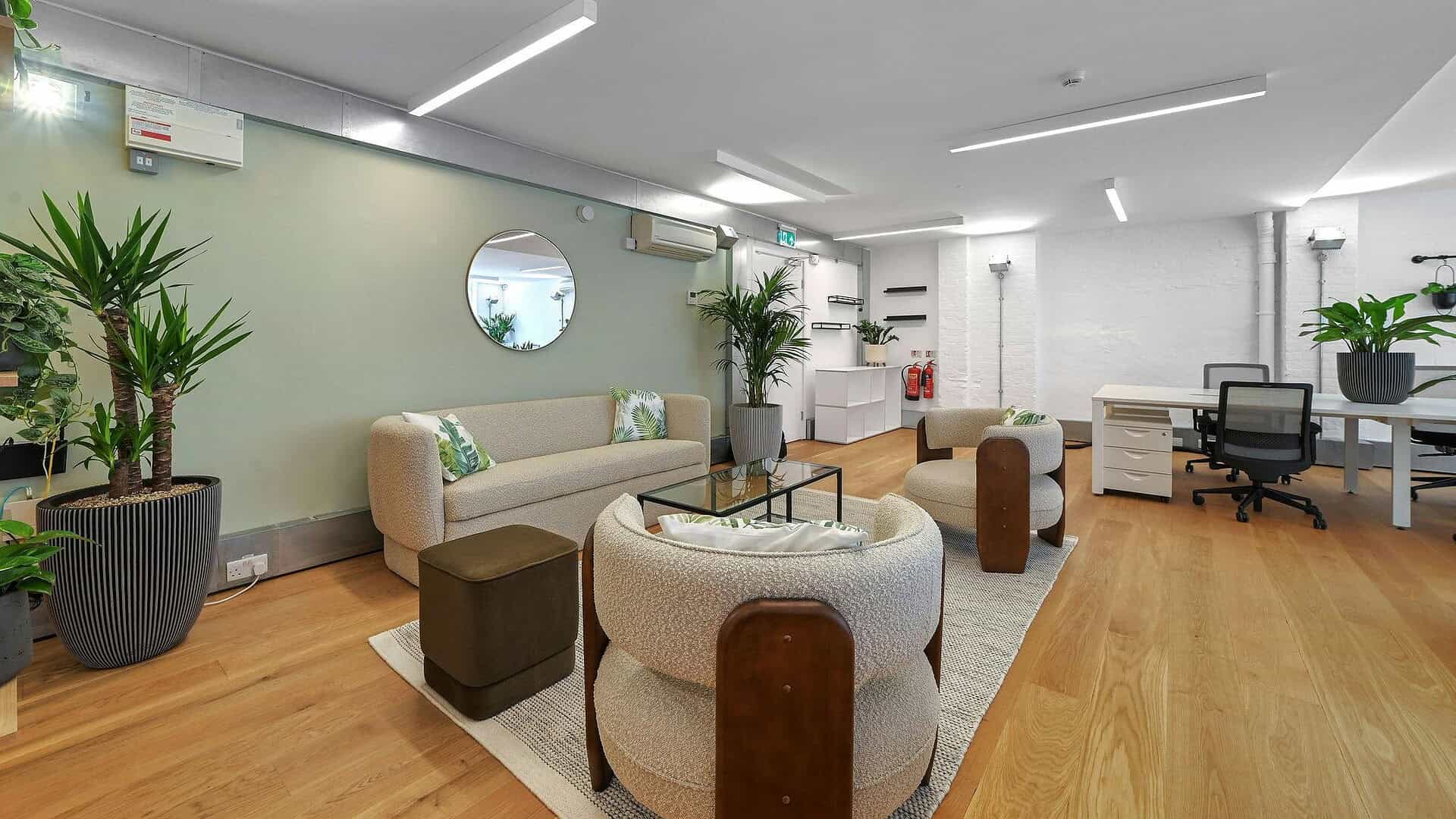 A modern, stylish office lounge with comfortable seating, potted plants, and contemporary decor, designed for relaxation and informal meetings in a professional environment.