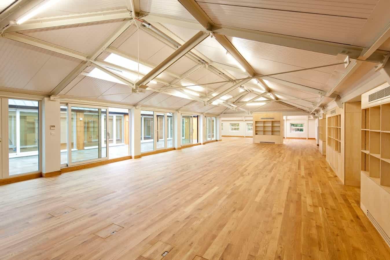 Bright, spacious interior with wooden flooring, large windows, and high ceilings, ideal for office or event space at BELCOR London.
