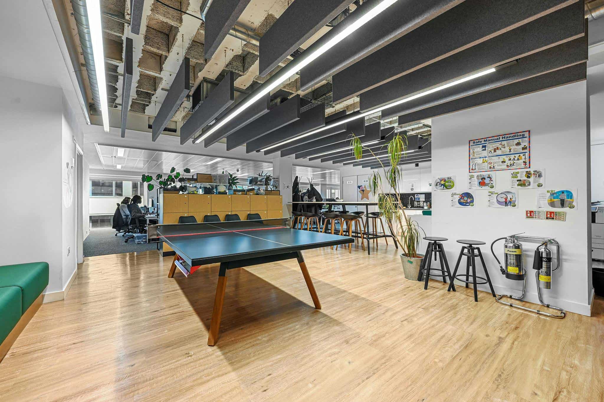 Modern office space with ping pong table, seating area, and creative decor, featuring open-plan design, bright lighting, and collaborative work environment at BELCOR London.